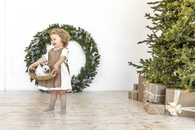 A little girl is holding a basket with a rabbit on the background of christmas decorations. new year