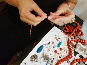 Midsection of woman making bead necklace