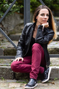 Portrait of woman sitting against railing