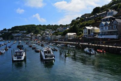 Sailboats moored on canal amidst buildings in city against sky