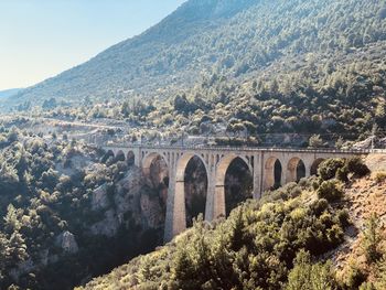 Arch bridge over mountains against sky