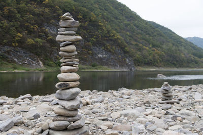 Stack of stones in lake against sky