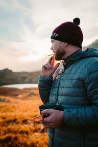 Man photographing with mobile phone against sky