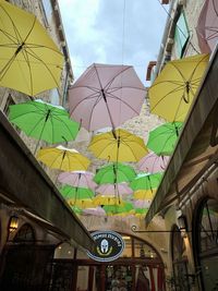 Low angle view of multi colored umbrellas hanging against sky