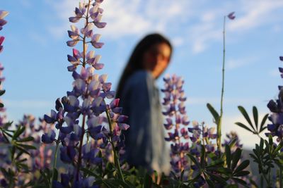 Close-up of flowers blooming against woman standing on field