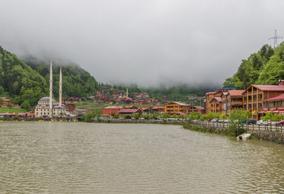 Scenic view of river by buildings against sky