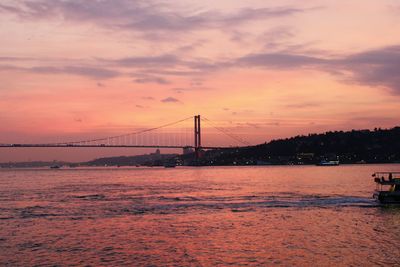 Suspension bridge over sea against sky during sunset