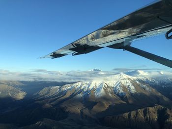 Aerial view of snowcapped mountains against blue sky