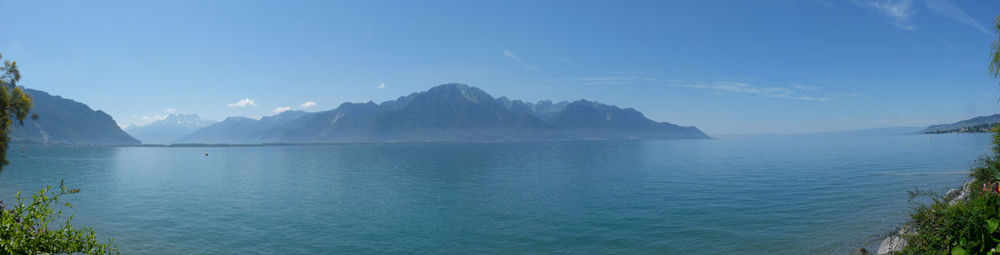 Panoramic view of sea and mountains against blue sky