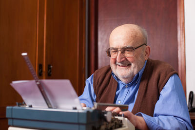 Smiling senior man using typewriter