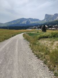 Road leading towards mountains against sky