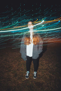 Digital composite image of woman and light painting at night