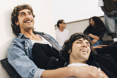 Happy gay couple spending leisure time with each other on building rooftop