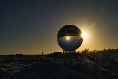 Scenic view of ball on land against sky during sunset