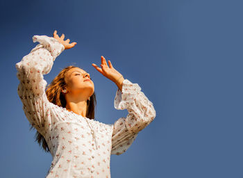 Young girl touching sun against blue sky background