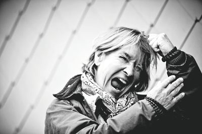 Close-up of frustrated woman pulling hair by fence