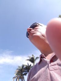 Close-up of hand holding plant against sky