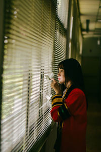 Side view of woman looking through window