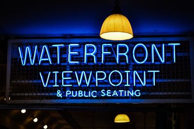 Low angle view of illuminated information sign at night