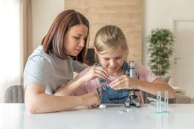 Mother helping daughter in science project at home