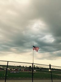 Fence on field against cloudy sky