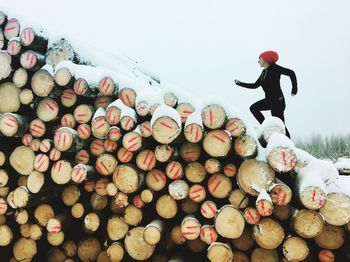 Full length of woman running on snow covered logs