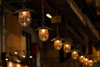 Low angle view of illuminated light bulb hanging from ceiling