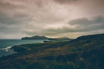 Scenic view of sea and mountains against cloudy sky