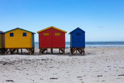 Beach hut by sea against blue sky