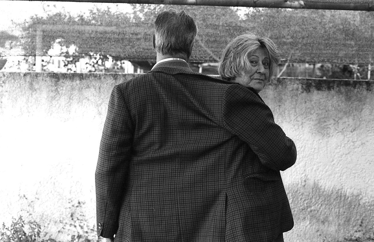 REAR VIEW OF COUPLE STANDING AGAINST THE WALL