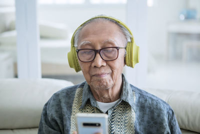 Man listening music through headphones sitting at home