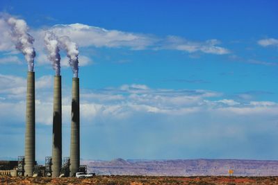 Chimneys emitting smoke against sky