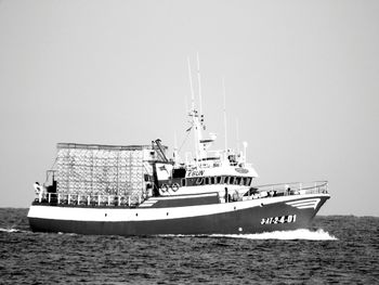 Boat sailing on sea against clear sky