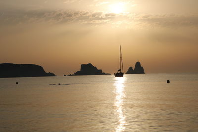 Silhouette sailboats in sea against sky during sunset