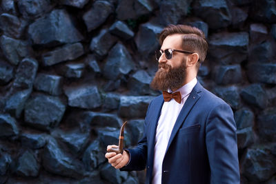 Portrait of young man standing against wall