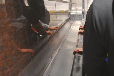 Midsection of man standing on escalator