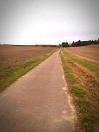 Road amidst agricultural field against clear sky