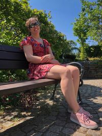 Portrait of teenage girl sitting by tree against plants