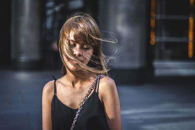 Young woman with tousled hair standing in city