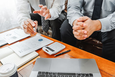 Midsection of business people shaking hands in office