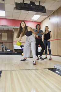 A young women bowling with friends.