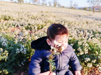 Boy holding flowers on field