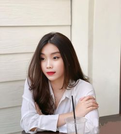 Portrait of young woman standing against wall