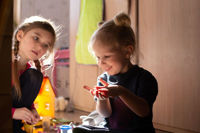 Two girls playing together in morning sun light sitting on the floor. carefree childhood concept. 