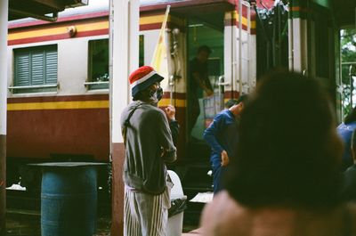 Rear view of people standing at railroad station