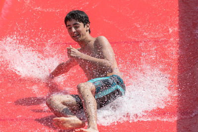 High angle view of young man enjoying water slide at park