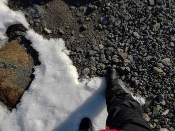 Low section of man walking on rocks during winter