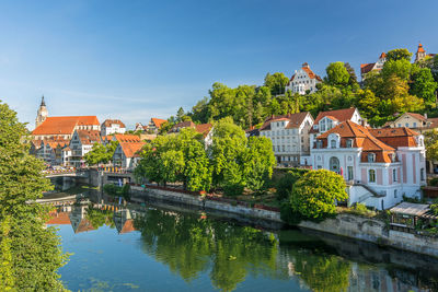 Houses by river and buildings against sky