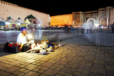 People in illuminated city against sky at night