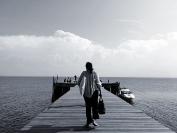 Rear view of woman standing on pier against sea